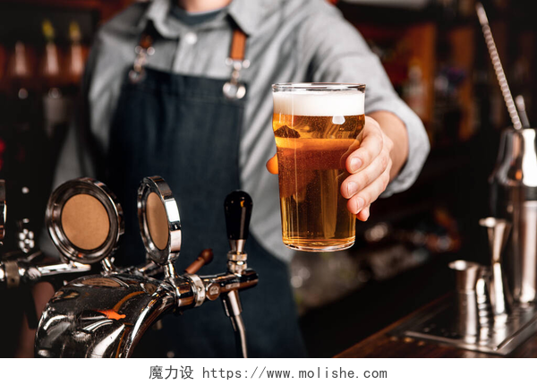 酒吧里为顾客提供美味饮料。酒吧招待在酒吧内部为顾客提供淡啤酒